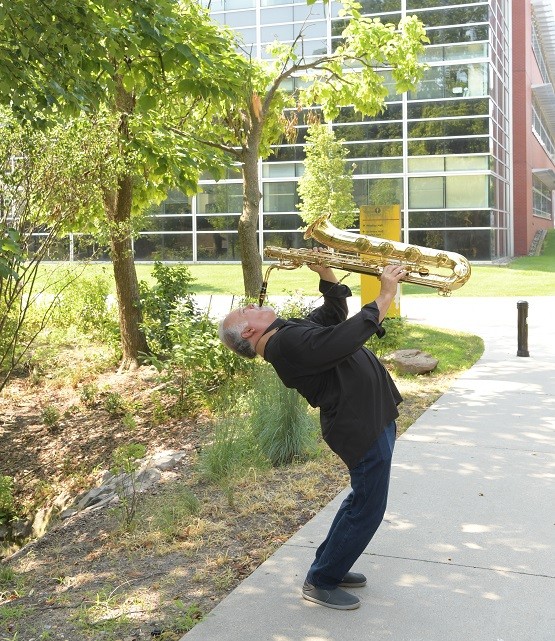 Denis DiBlasio playing the sax while standing and his back arched back
