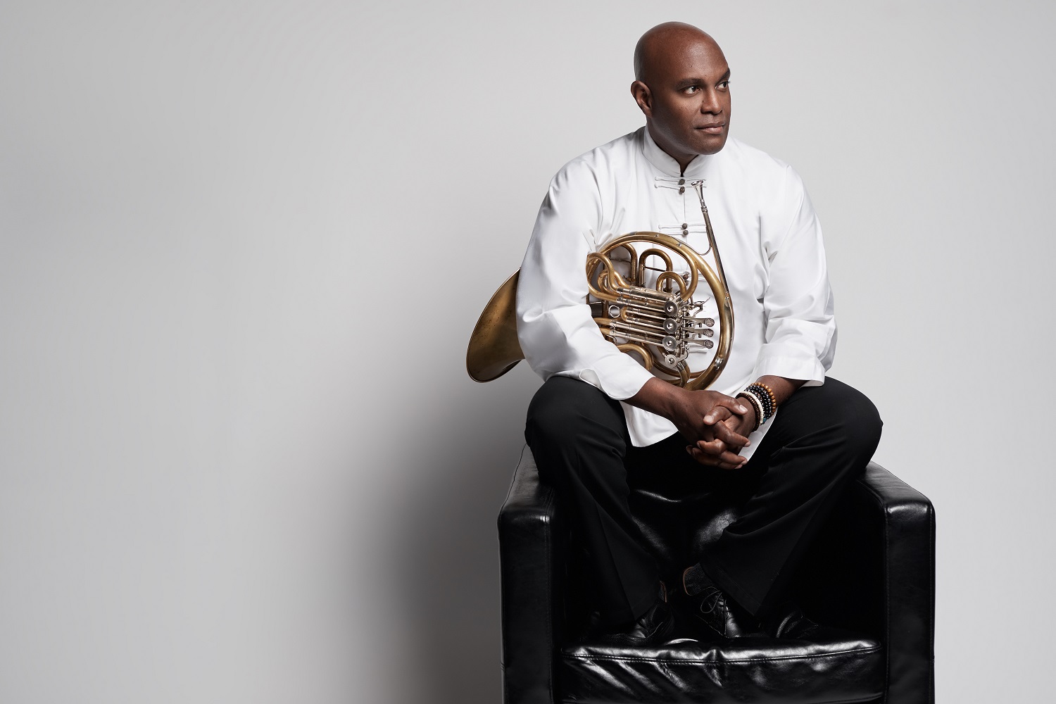 Larry Williams holding French horn, wearing white shirt and black pants