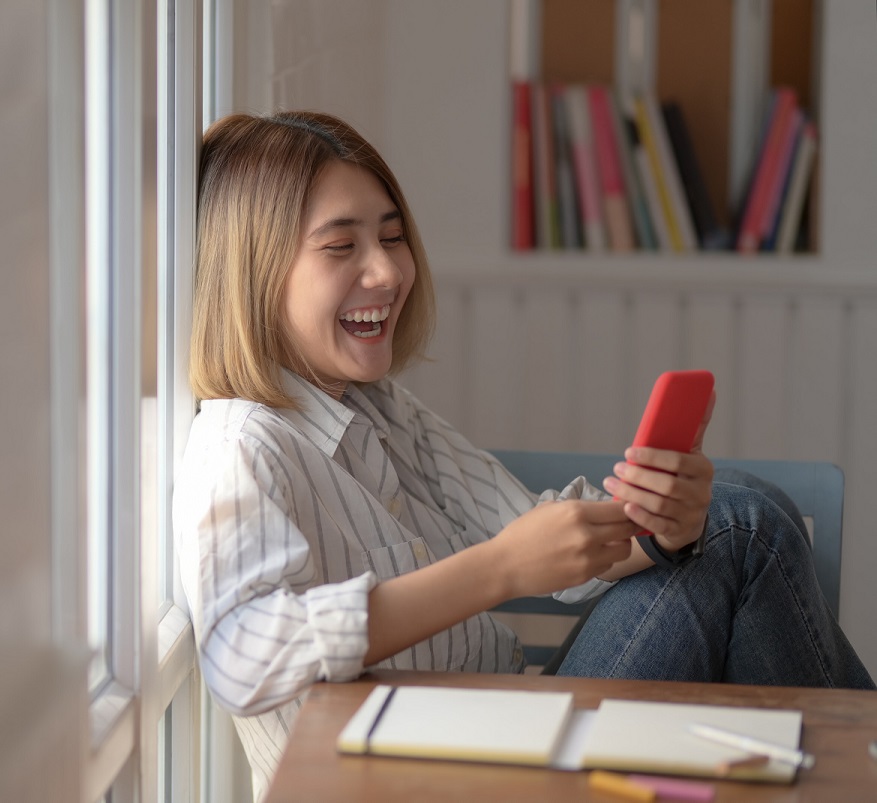 woman laughing while looking at cell phone 