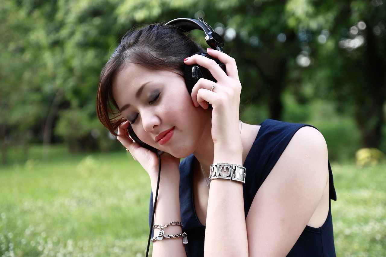 woman with eyes closed, holding headphones to her ears 
