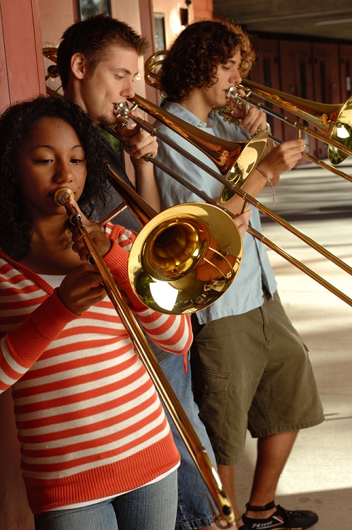 three students playing the trombone