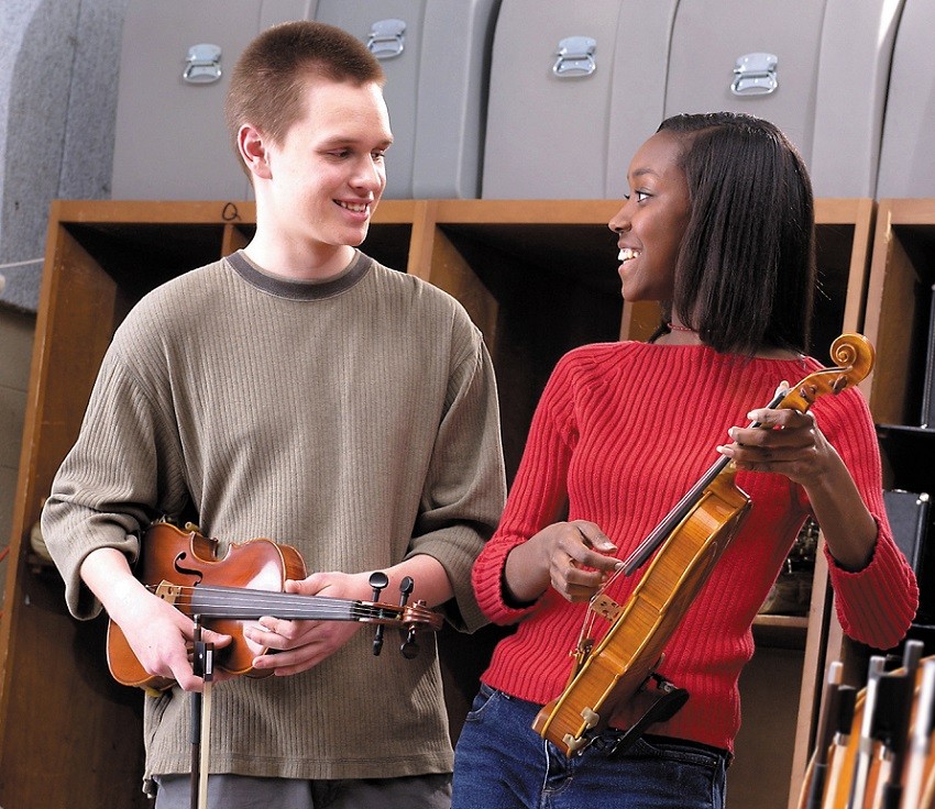 male and female student holding violins 