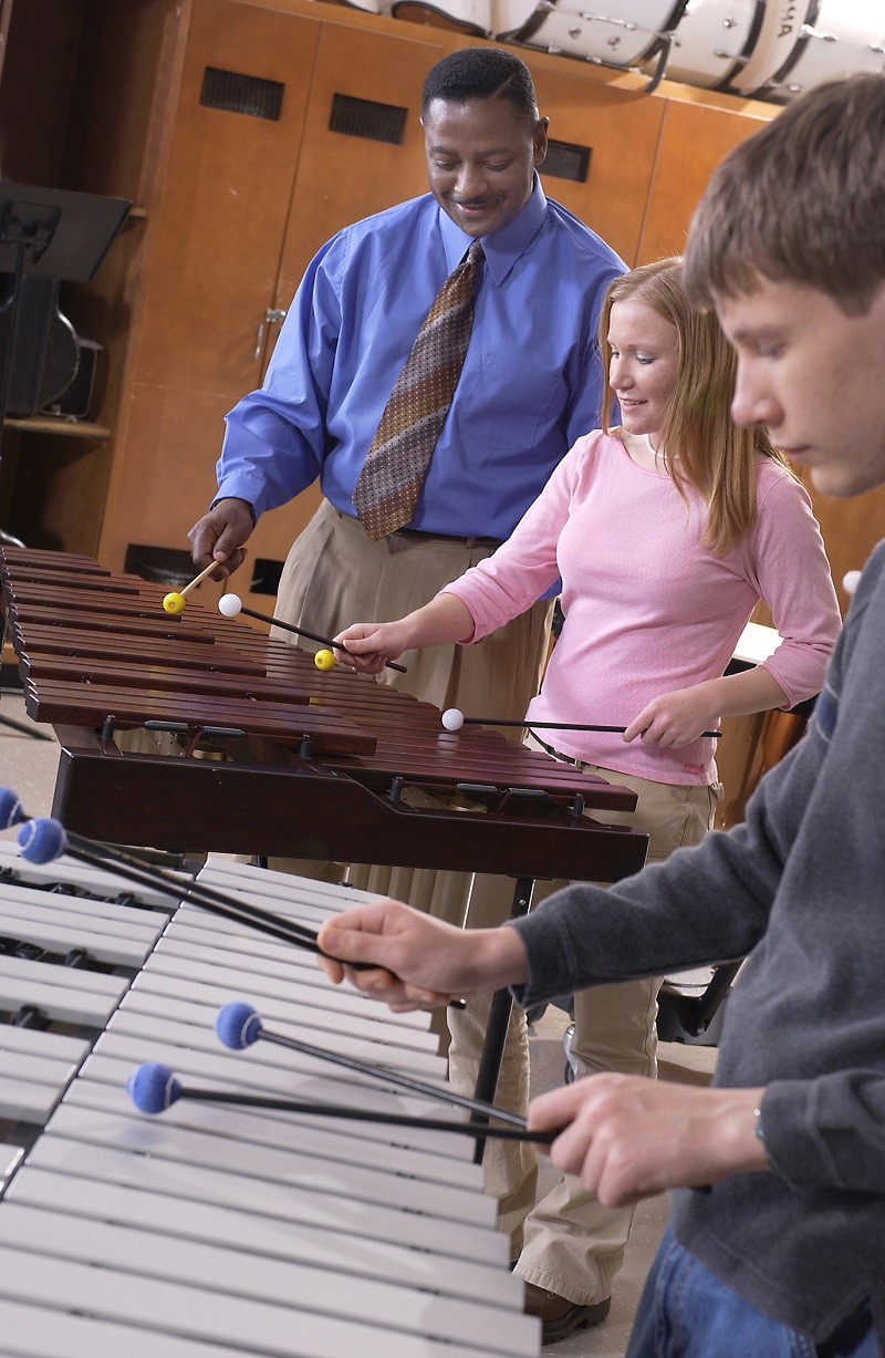 band director overseeing percussion students playing the vibraphone and marimba