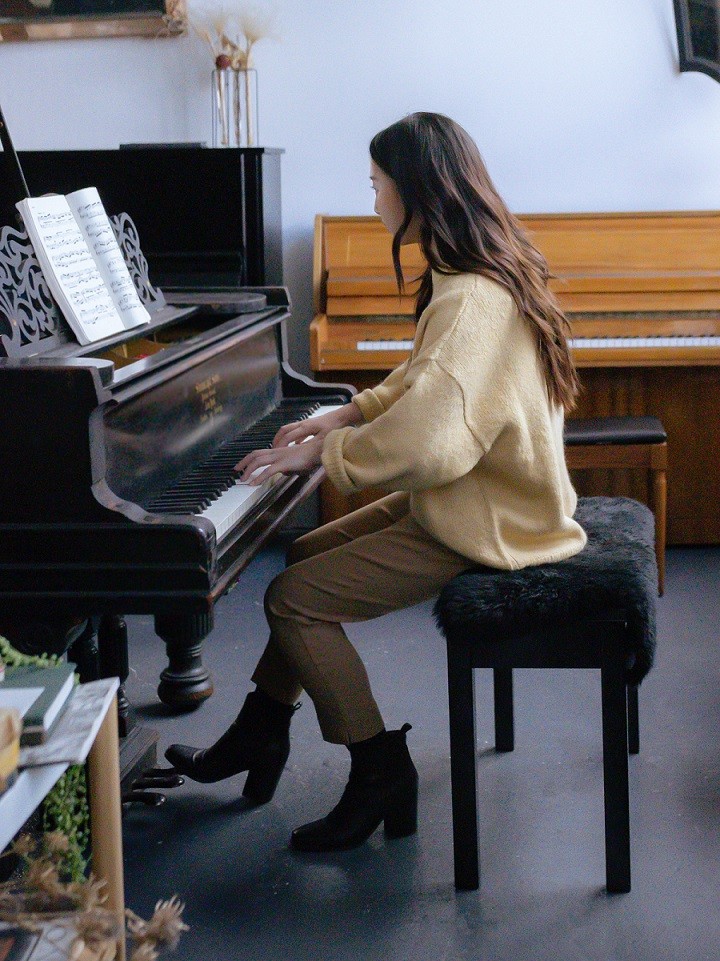 female playing piano from side