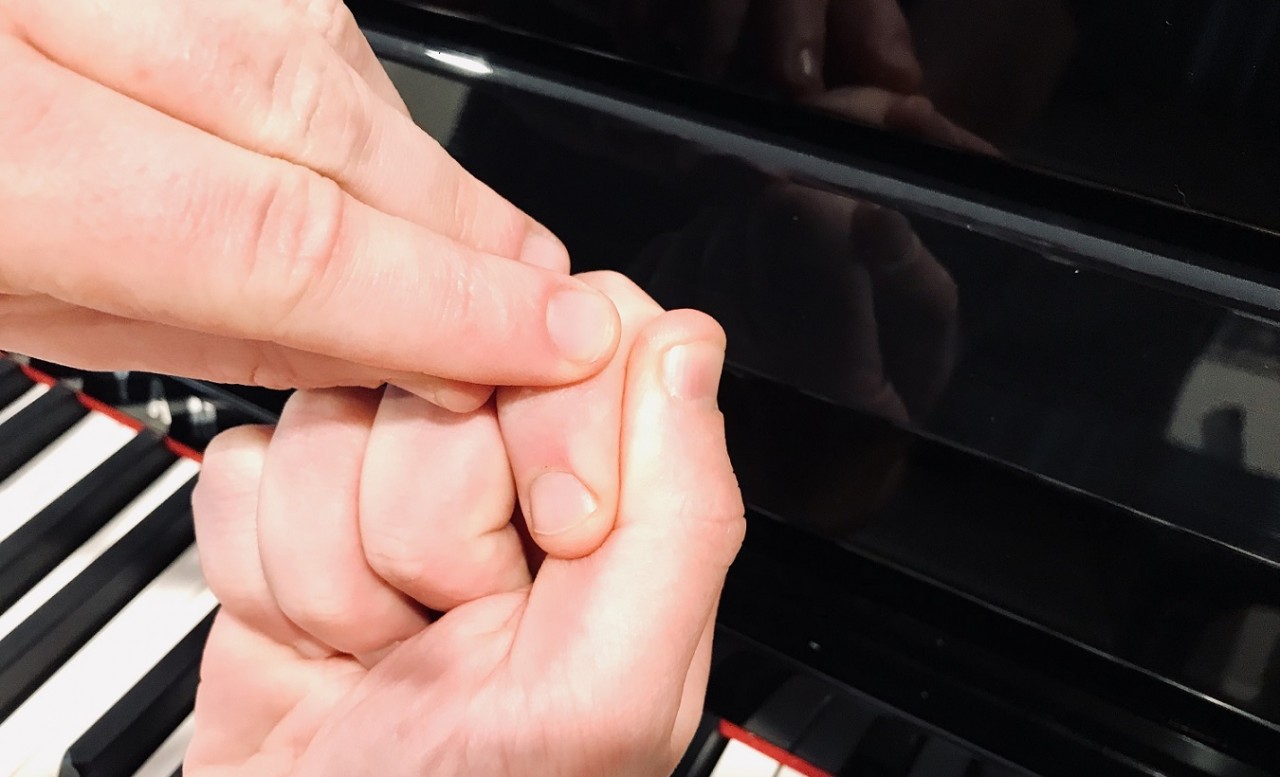 finger pointing to where the thumb should hit the piano key 