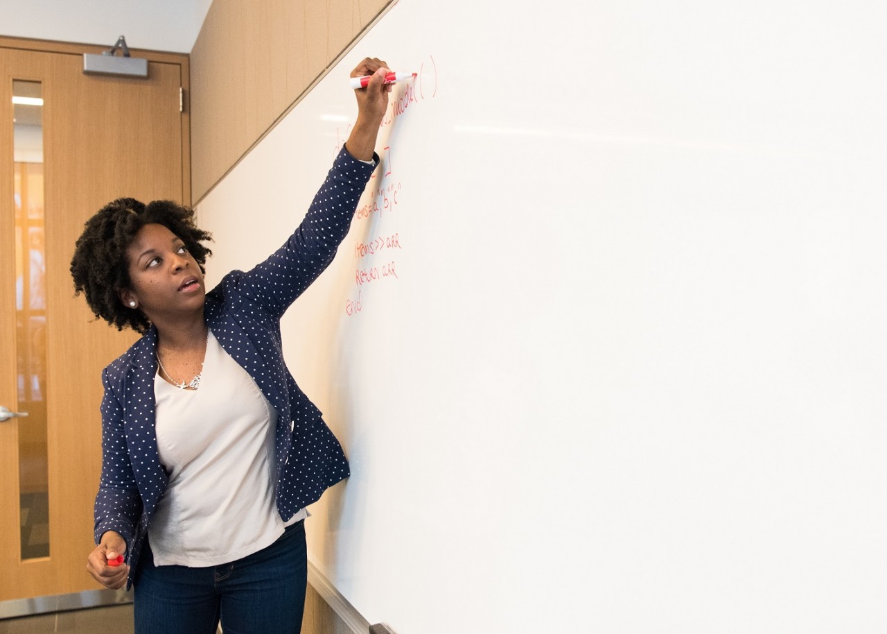 female teacher writing on white board 
