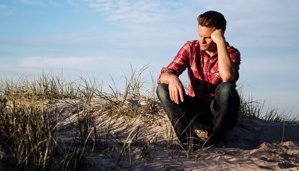 man in doubt sitting at beach