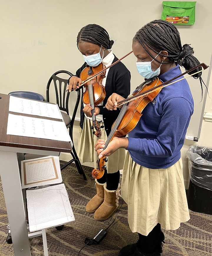 two female students playing the violin