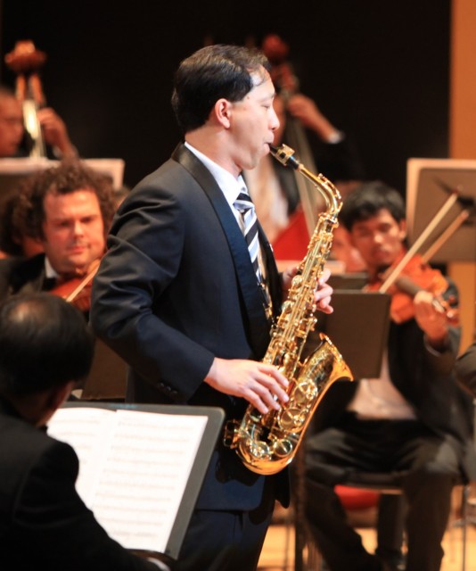 Kenneth Tse playing saxophone with orchestra