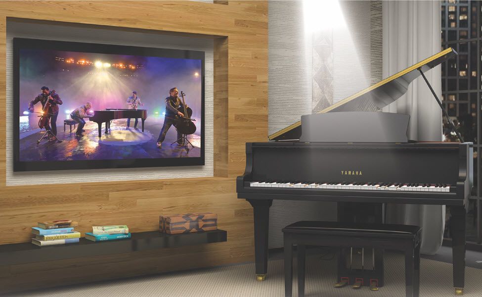 Musicians performing in video on big screen tv on wall in living room while modern player piano in room is accompanying.