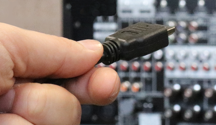 Closeup of hand plugging in a cable to the rear panel of a receiver.