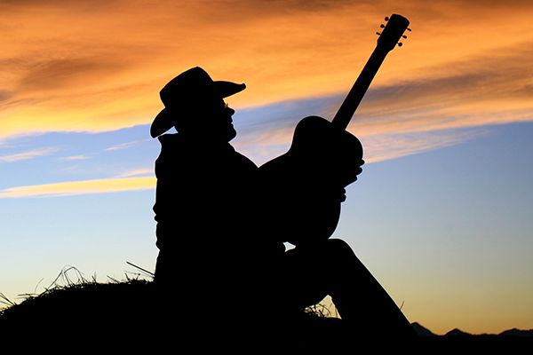 Country musician plays guitar at sunset.