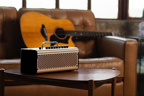 Yamaha THR30IIA desktop amp on wooden coffee table with acoustic guitar in background.