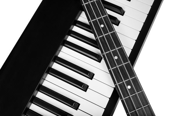 Closeup of the neck and strings of a guitar on top of a keyboard.