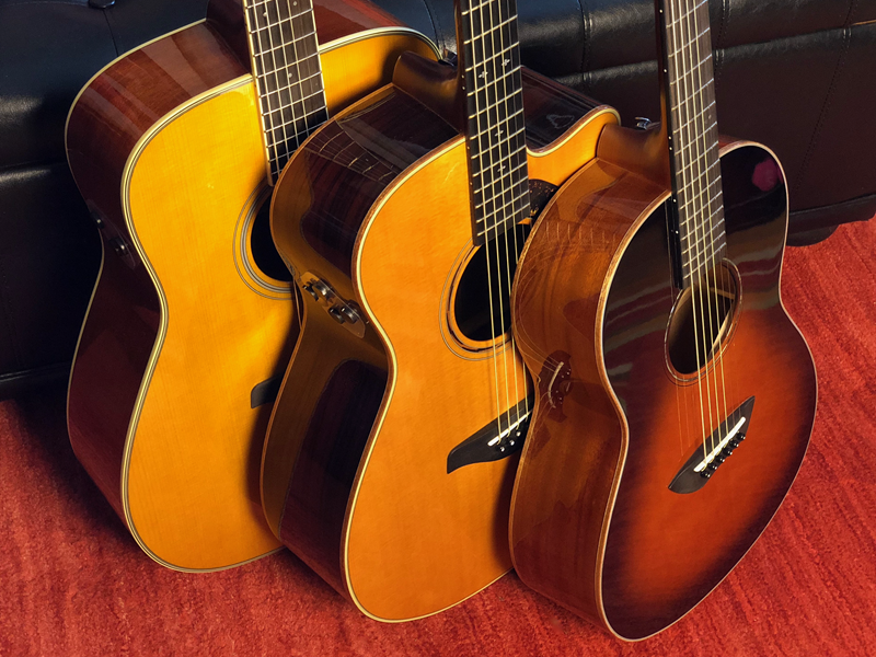 Three acoustic guitars lined up from left to right largest to smallest.