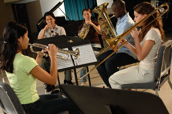 Five young people practicing as brass quintet in a practice room.