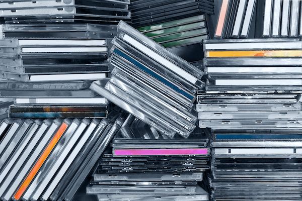 Piles of CDs in their cases stacked haphazardly on a shelf.