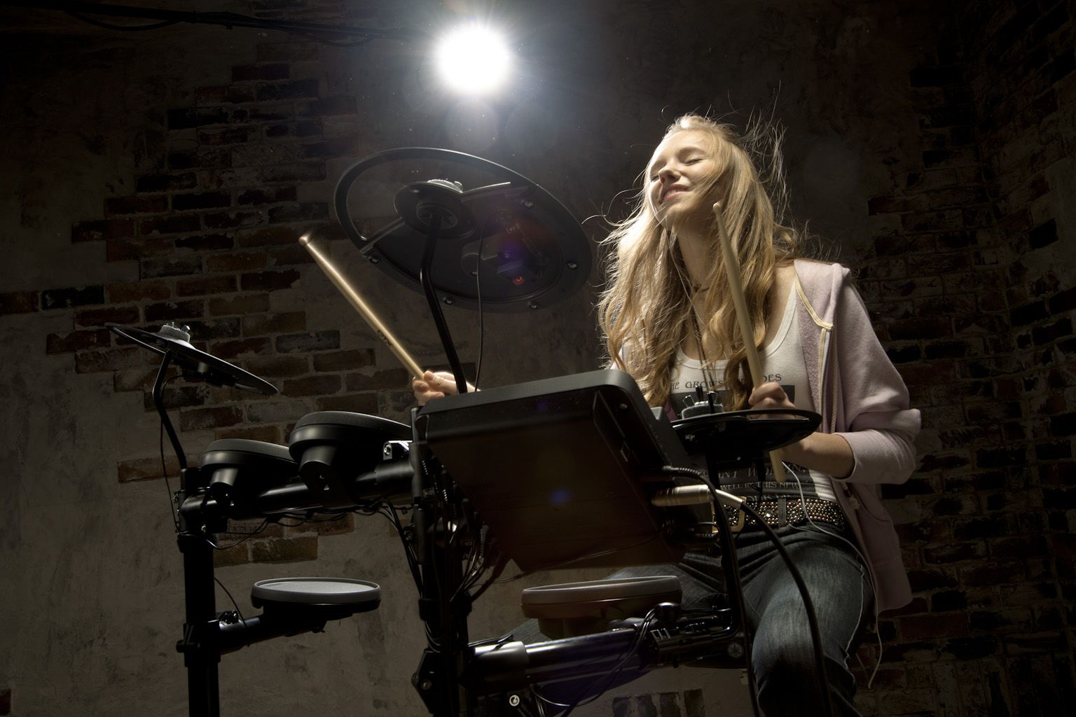 Teenage girl playing electronic drum kit.