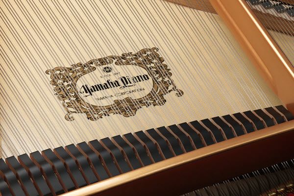 Closeup of strings inside a piano with a logo underneath that indicate "Yamaha Piano."