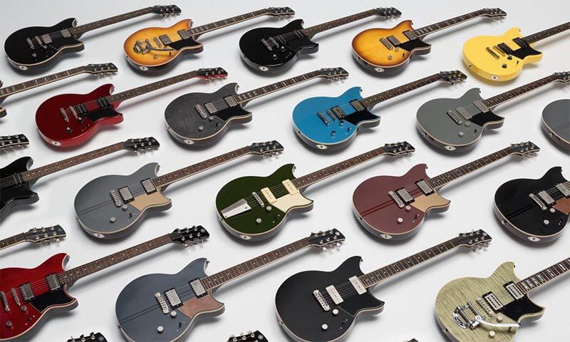 Multiple rows of electric guitars laying face-up.