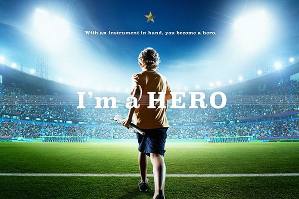 An image of a child standing in front of a stadium with lights in front of him. Text overlay says "I'm a hero."