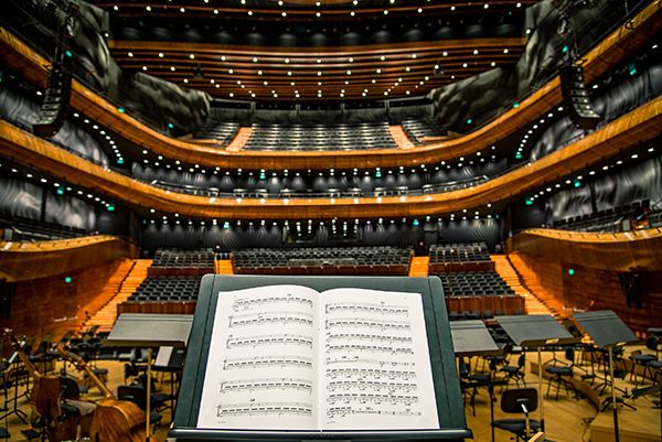 An image of a musical note sheet set up in front of a concert hall.