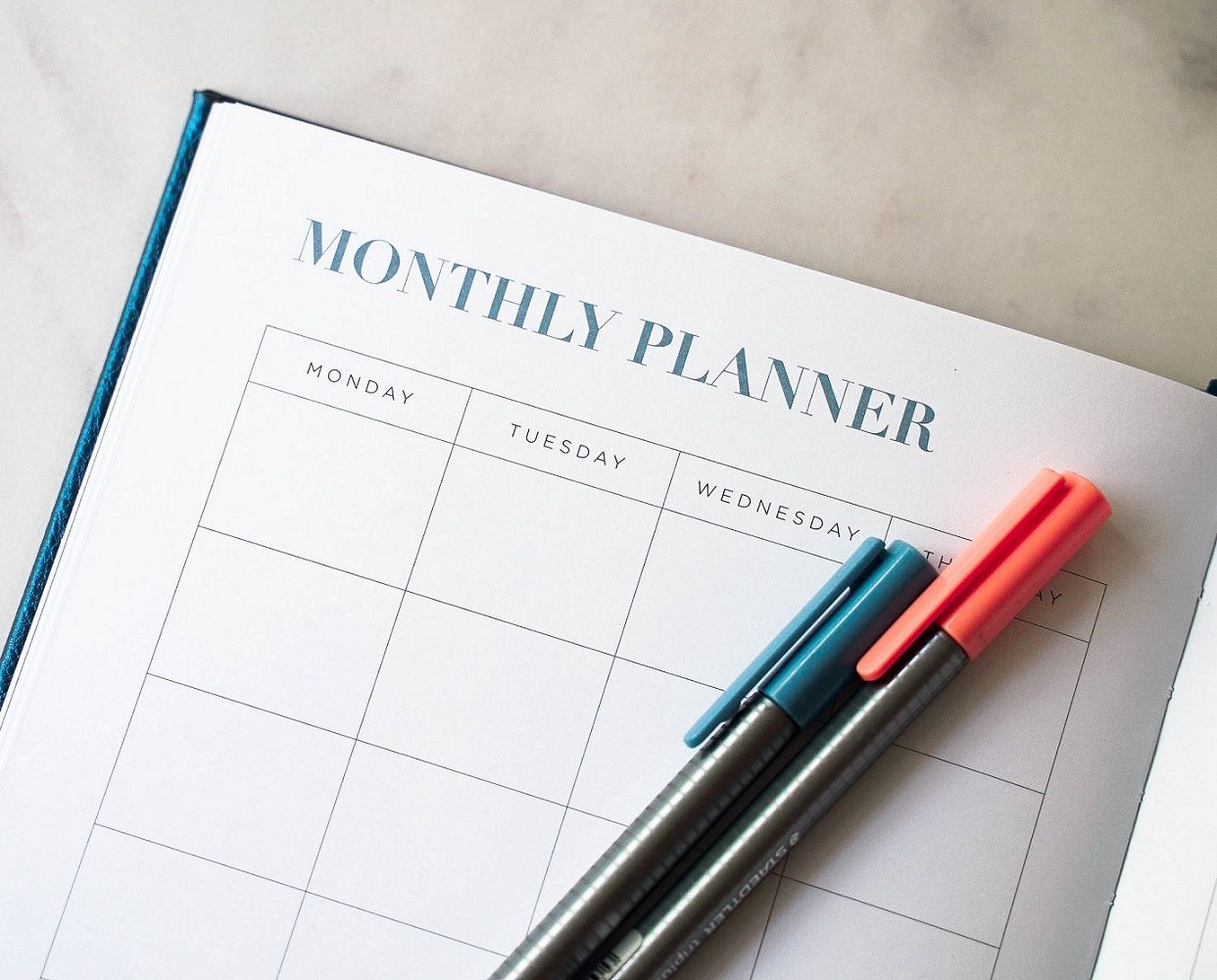 monthly planner with two pens lying on an open page