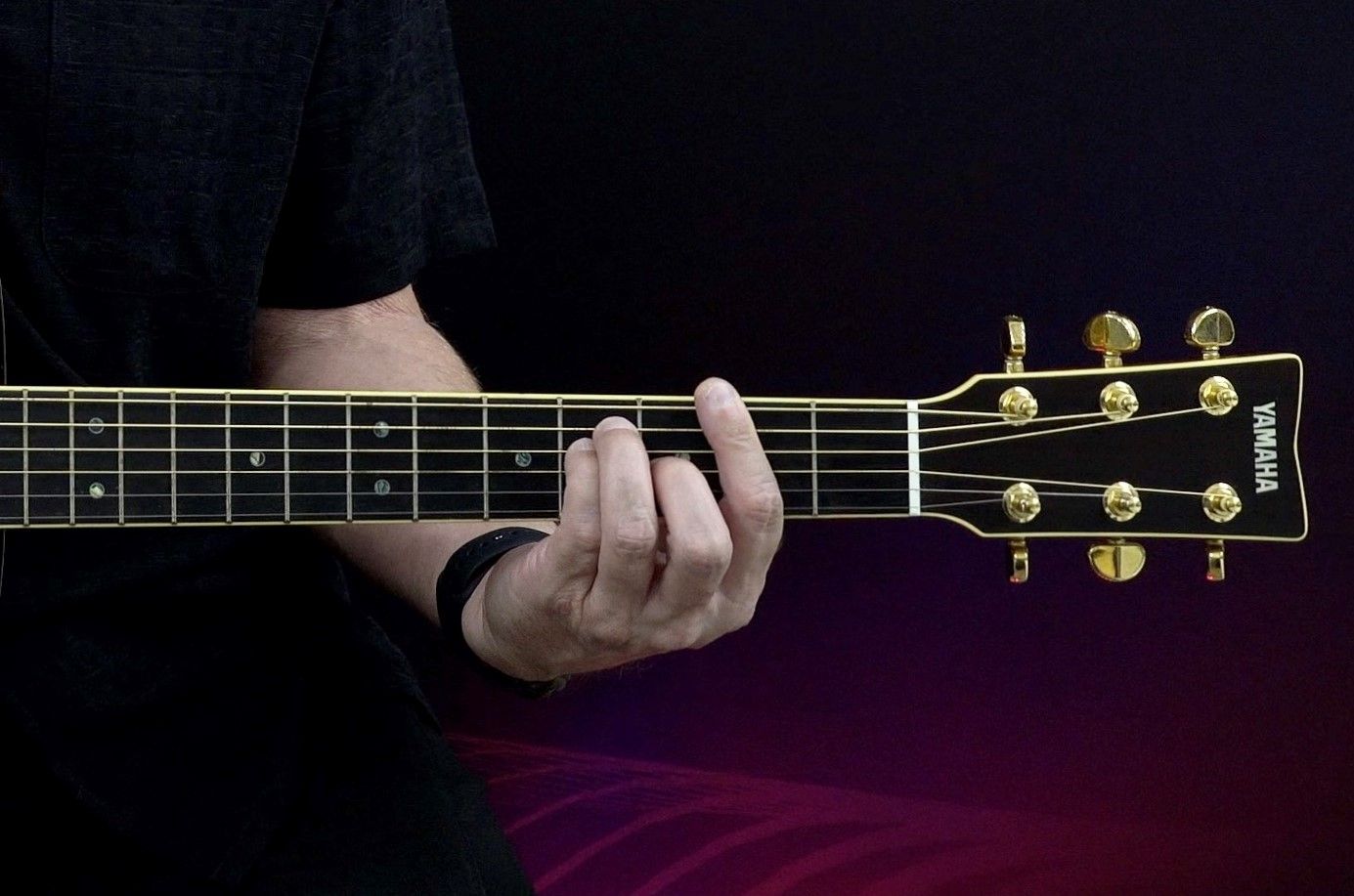 Closeup of hand playing guitar neck.