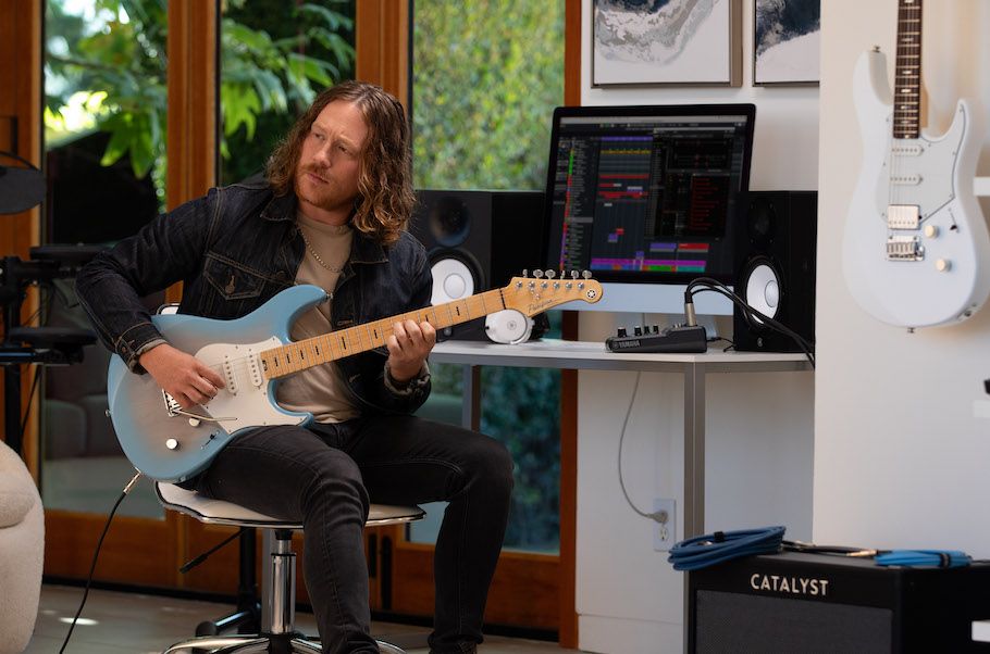 Man playing an electric guitar in studio.