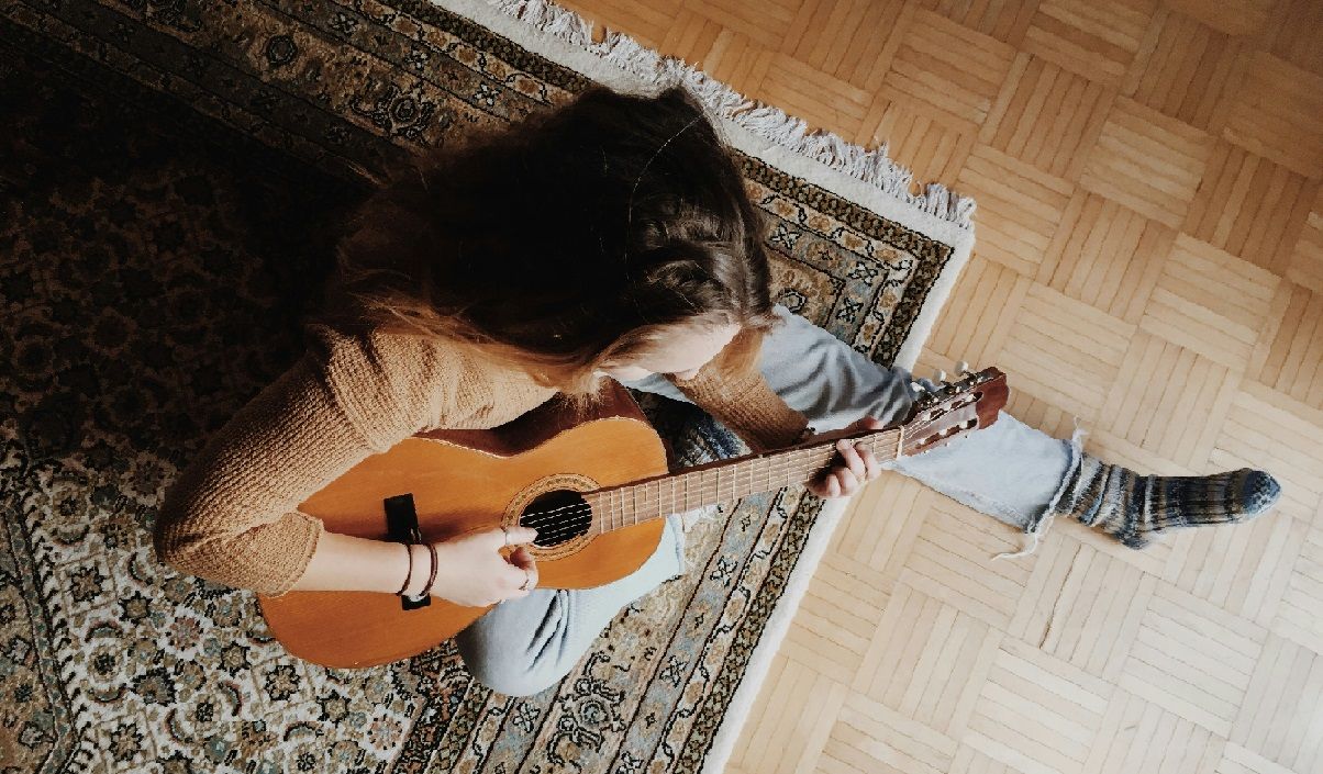woman sitting on floor and playing the guitar
