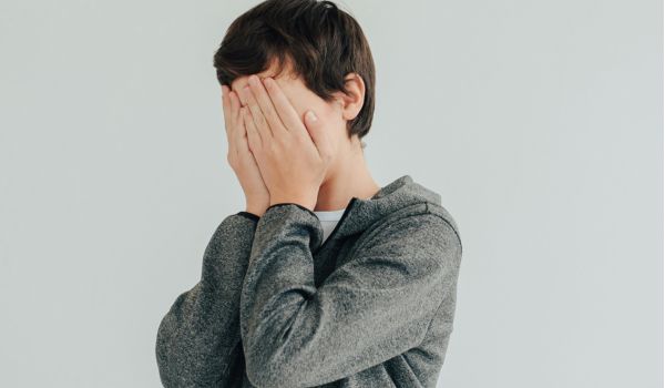 teen with face in hands in panic