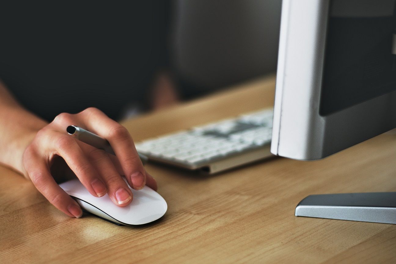 someone using desktop computer with hand on mouse