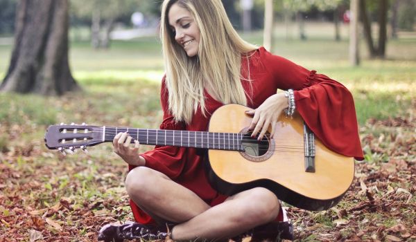 female playing guitar outdoors