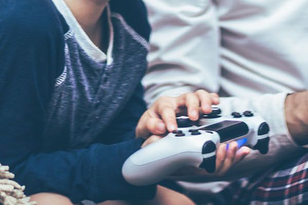 Small boy and his father playing video games and communicating in the living room.