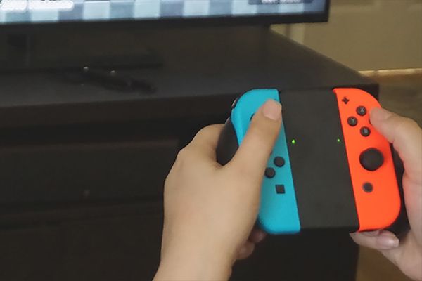 Person holding switch controller near tv screen.