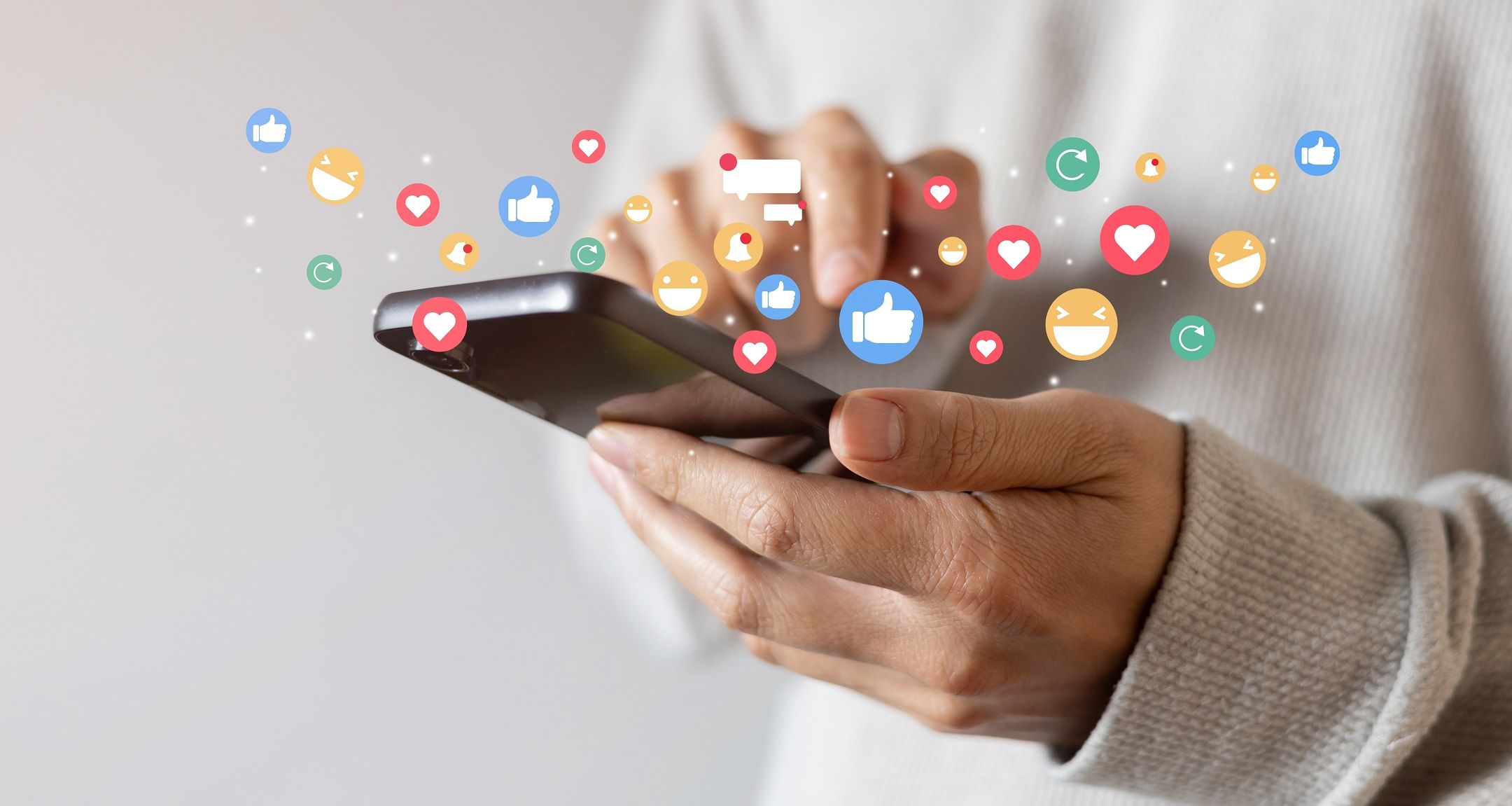 closeup of someone holding hands with like, comments, rewatch icon bubbles floating above the phone