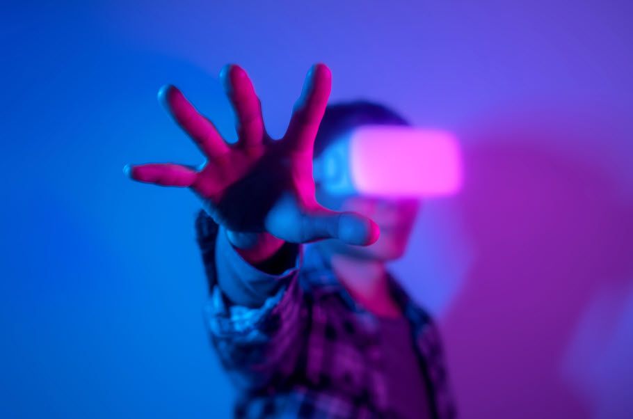 Someone wearing virtual reality goggles and reaching out with hand.