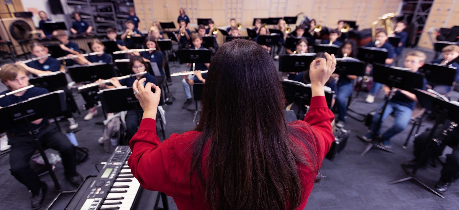 female conductor with back to camera in front of ensemble