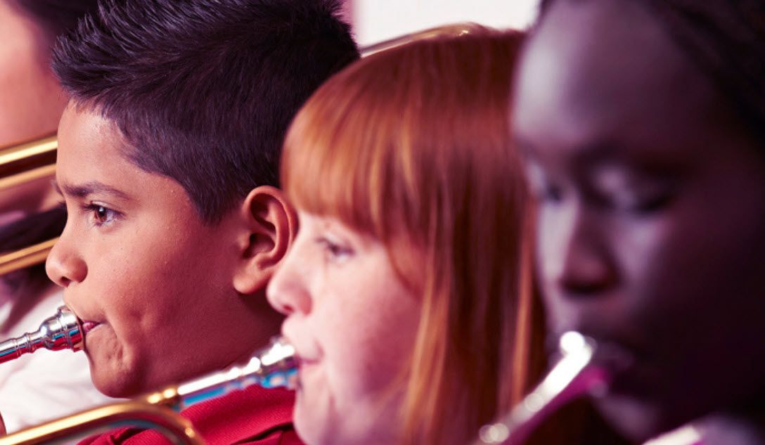 Young students playing brass horns.