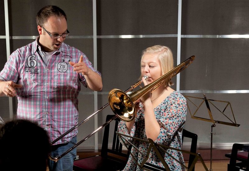 Teacher showing student how to play trombone.