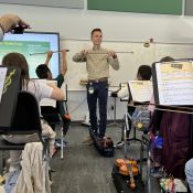 Music educator Tanner Otto showing students how to hold a bow