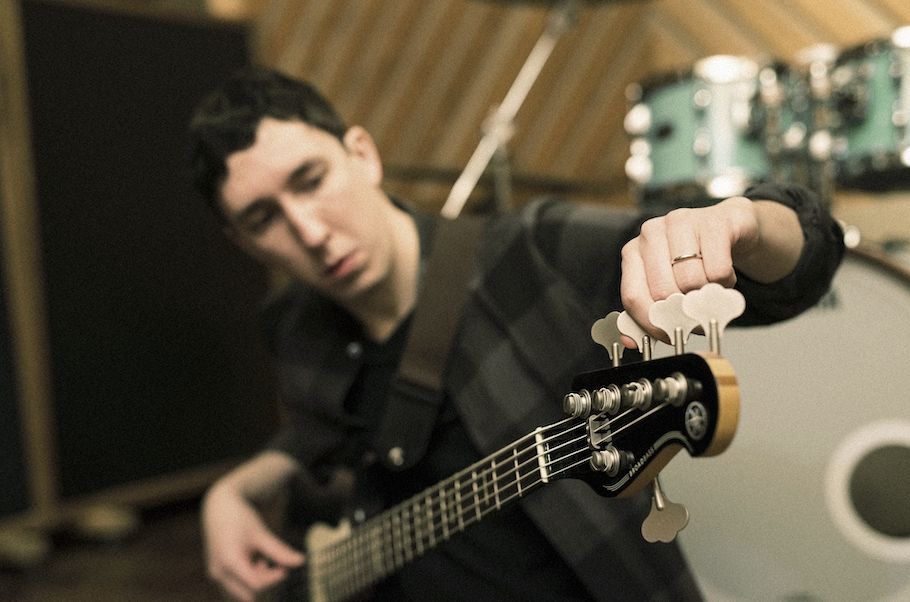 Closeup of someone tuning a 5-string guitar.