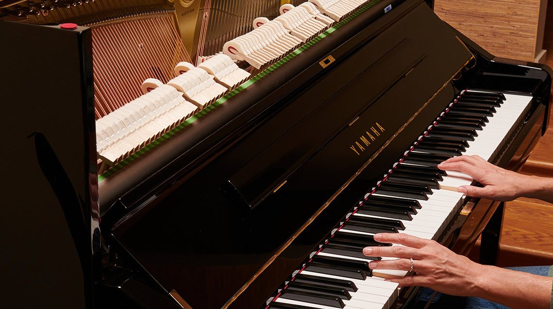 Closeup of someone playing an upright acoustic piano.