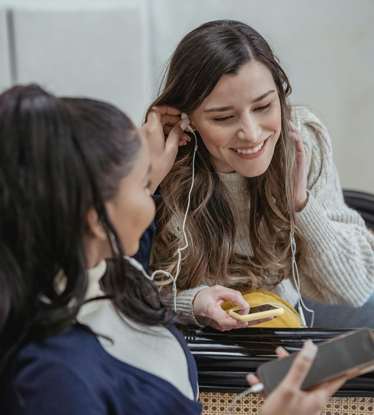 two teens smiling and sharing earbuds