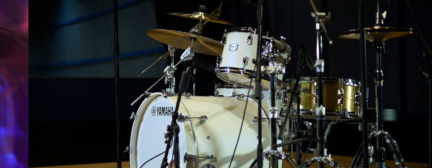 White drum set on stage with dark background