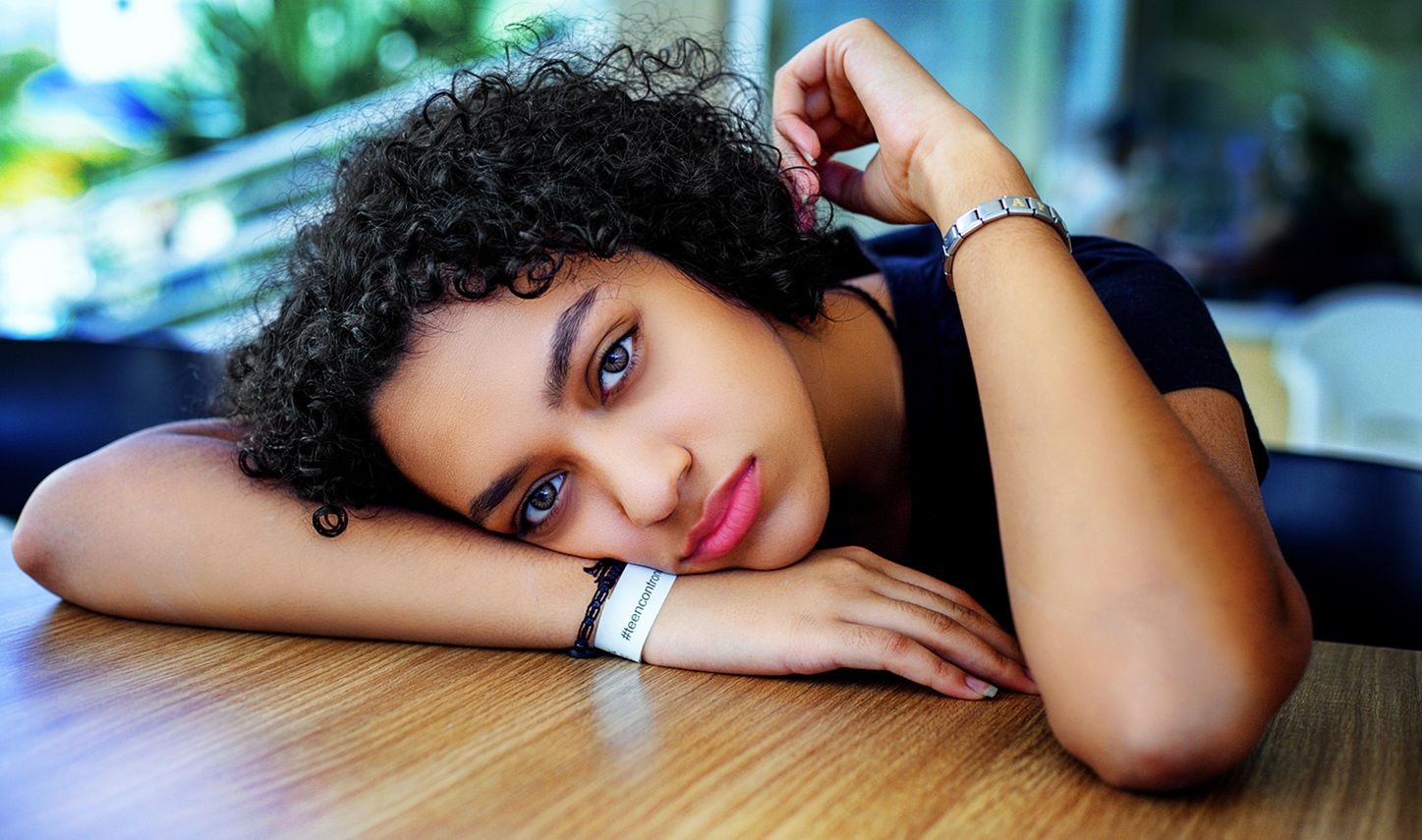 female student looking sad as she rests head on desk