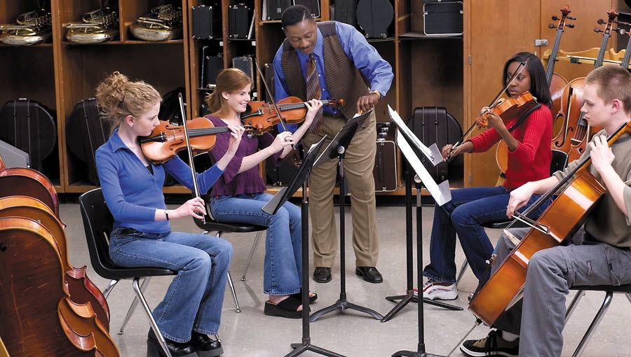Teacher instructing group of children in how to play strings.