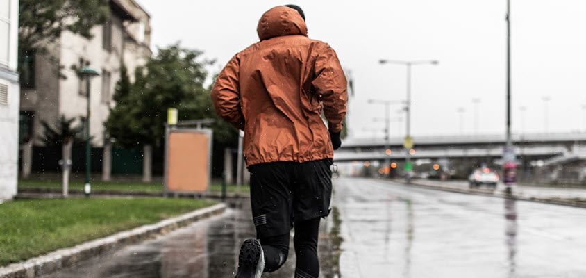 Person running on a city street while it is raining.