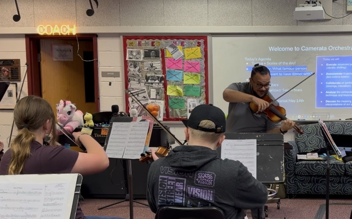 orchestra teacher playing violin along with his students