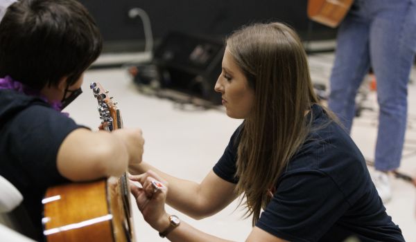 music teacher helping student with guitar